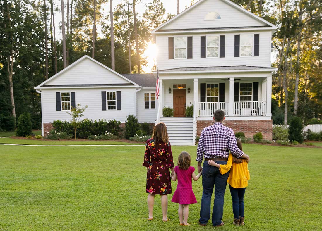 Home buyers and their family in front of new home